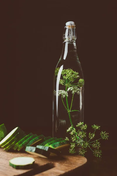 Glass bottle with water and dill, cut zucchini on wooden board — Stock Photo