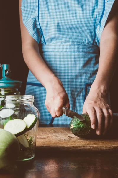 Cropped image of woman cutting zucchini on wooden board at kitchen — Stock Photo