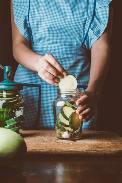 Обрізане зображення жінки, що додає кабачки в скляну банку на кухні — стокове фото