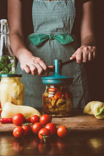 Imagem cortada de mulher preparando vegetais preservados em frasco de vidro na cozinha — Fotografia de Stock