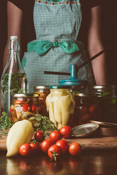 Imagem cortada de mulher em pé perto de vegetais preservados em frascos de vidro na cozinha — Fotografia de Stock