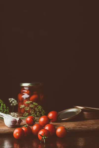 Preserved tomatoes and fresh tomatoes on kitchen table — Stock Photo