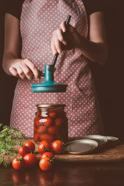 Cropped image of woman preparing preserved tomatoes at dark kitchen — Stock Photo