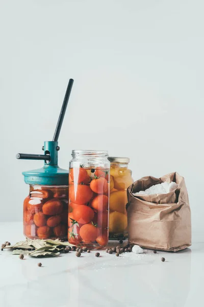 Glass jars and tool for preserving tomatoes on table in kitchen — Stock Photo