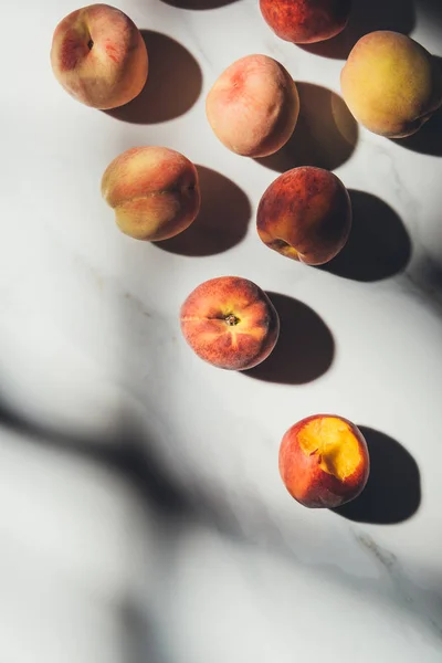 Плоский лежал с спелыми персиками на светлом мраморном столе с тенями — стоковое фото