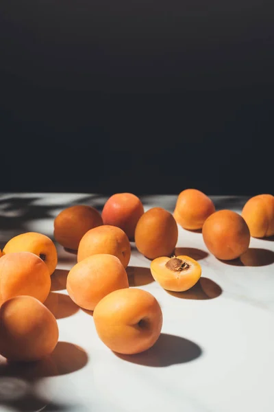 Essenszusammensetzung mit frischen Aprikosen auf heller Marmoroberfläche mit schwarzem Hintergrund — Stockfoto
