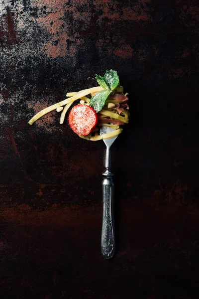 Vista dall'alto della forchetta avvolta dalla pasta con foglie di menta, marmellata e pomodorini ricoperti da parmigiano grattugiato sul tavolo — Foto stock