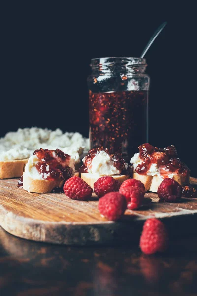 Selective focus of raspberries, sandwiches with fruit jam and cream cheese on cutting on black — Stock Photo