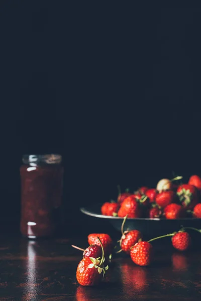 Focalizzazione selettiva di fragole in vassoio d'argento e marmellata di frutta in vaso su nero — Foto stock