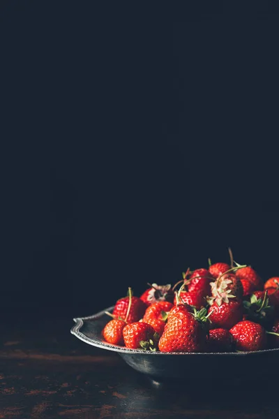 Selective focus of pile of strawberries in silver tray on black — Stock Photo