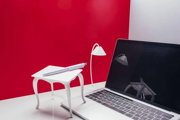 Portátil de tamaño real con mesa de juguete y lámpara en la habitación en miniatura - foto de stock