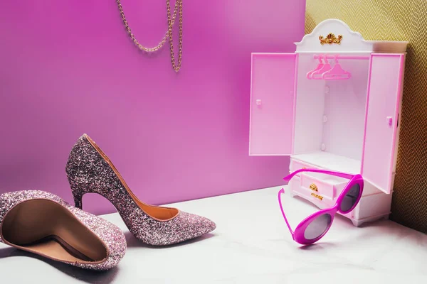 Toy wardrobe with real size high heels and vintage sunglasses in miniature pink room — Stock Photo