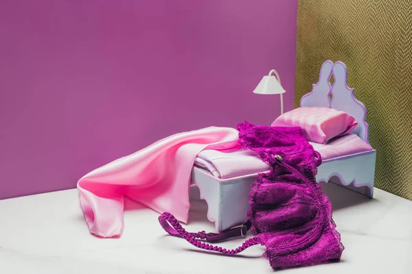 Toy bed and torch lamp with real size bra in miniature room — Stock Photo