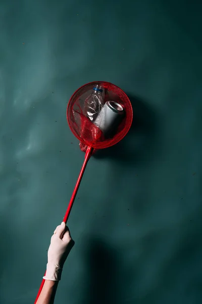 Colpo ritagliato di persona in guanto di lattice con rete a farfalla pulizia dell'acqua dalla spazzatura — Foto stock