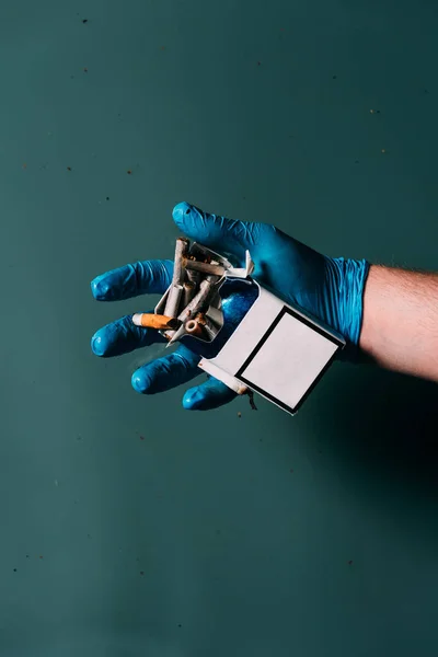 Teilbild eines Mannes im Latexhandschuh mit Zigaretten in der Hand, Ökosystemschutzkonzept — Stockfoto