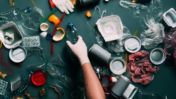 Visión parcial del hombre en guante de látex limpieza de agua de la basura, concepto de protección ecológica - foto de stock