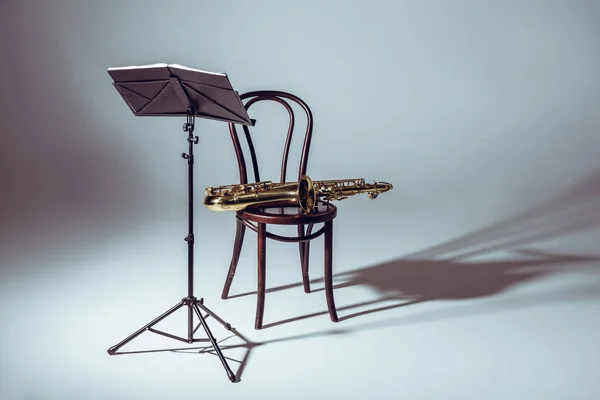 Soporte de música para notas y saxofón en silla en el estudio — Stock Photo