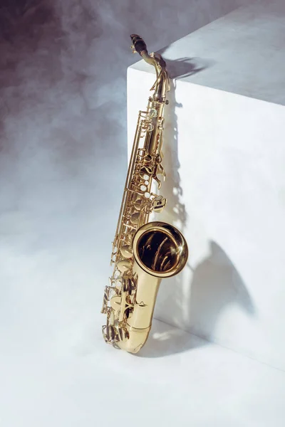 Vista de cerca del saxofón profesional en humo sobre gris - foto de stock