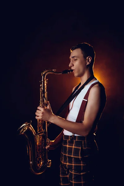 Vista lateral de jazzman joven profesional elegante jugando saxofón - foto de stock