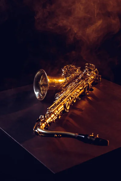 Професійний блискучий саксофон в диму і підсвічування на чорному — стокове фото