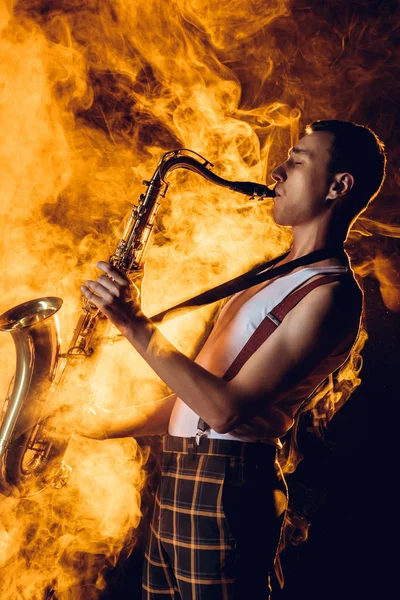Vista lateral do saxofonista profissional elegante jogando sax na fumaça — Fotografia de Stock