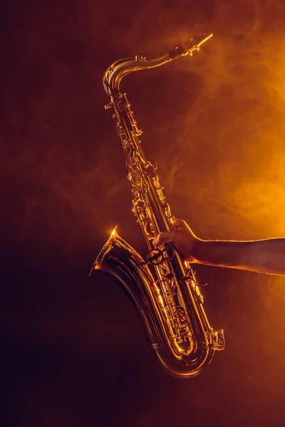 Close-up partial view of young musician holding saxophone in smoke — Stock Photo