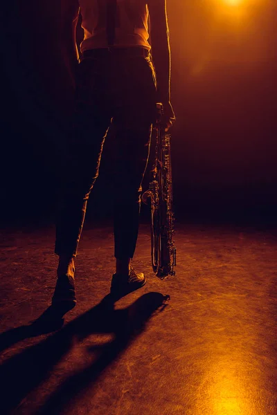 Обрезанный кадр музыканта, держащего саксофон на сцене — стоковое фото