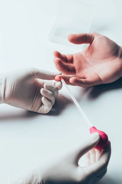 Tiro recortado do médico que toma o sangue do paciente para o teste na mesa branca — Fotografia de Stock