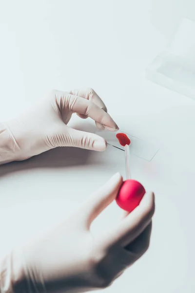 Cropped shot of doctor pouring blood from pipette onto blood slide — Stock Photo