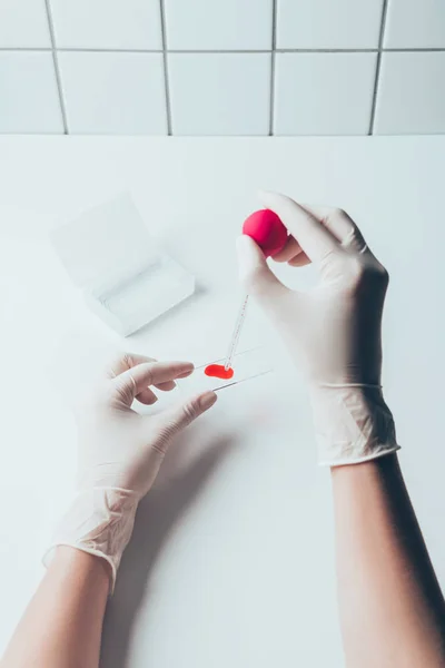 Cropped shot of doctor pouring blood from pipette onto blood slide for test — Stock Photo