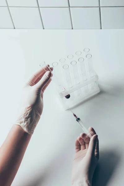 Cropped shot of doctor with syringe and glass test tubes — Stock Photo