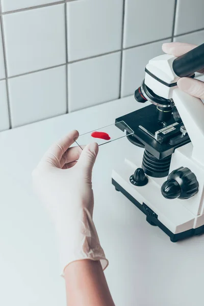 Plan recadré du médecin mettant l'échantillon de sang au microscope pour examen — Photo de stock