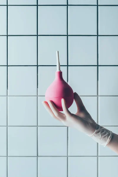 Tiro recortado de médico en guante con ducha delante de la pared blanca de azulejos - foto de stock