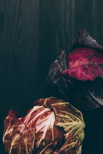 Erhöhter Blick auf Rotkohl und roten Salat auf grauem, dunklem Tisch — Stockfoto