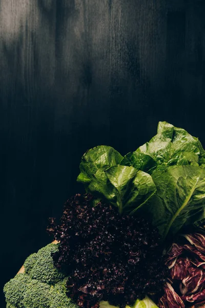 Vista dall'alto di broccoli e insalata verde sul tavolo grigio scuro — Foto stock