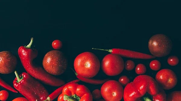Top view of red tomatoes, bell peppers and chili peppers on grey dark table — Stock Photo