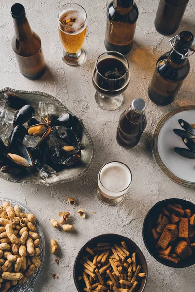 Vista superior de lanches, mexilhões com cubos de gelo e cerveja fria dispostos em mesa de concreto — Fotografia de Stock