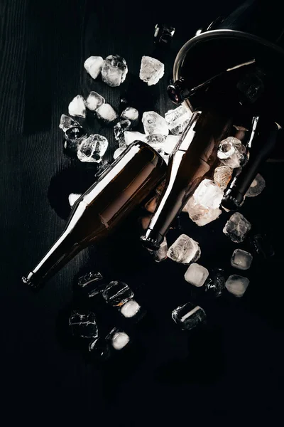 Flat lay with bucket, glass bottles of beer and ice cubes arranged on dark tabletop — Stock Photo