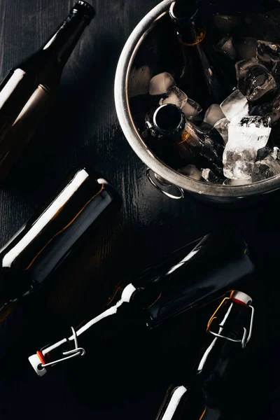 Piatta giaceva con secchio, bottiglie di birra e cubetti di ghiaccio disposti su un tavolo scuro — Foto stock