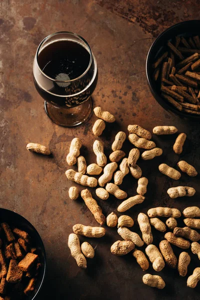 Vista superior de amendoins, pães assados e copo de cerveja na mesa de ferrugem — Fotografia de Stock