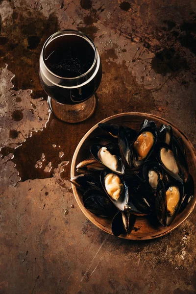 Top view of glass of cold beer and mussels in bowl on rust surface — Stock Photo