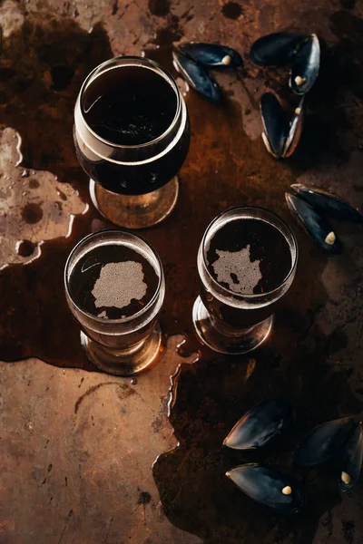 Vista superior de vasos de cerveza fría y conchas de mejillones en la superficie oxidada - foto de stock