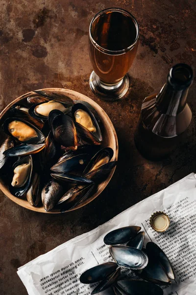 Draufsicht auf arrangiertes Glas und Flasche Bier, Zeitung und Muscheln in Schale auf Rostoberfläche — Stockfoto