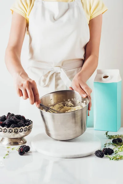 Cropped shot of woman in apron preparing cream for cake with whisk — Stock Photo