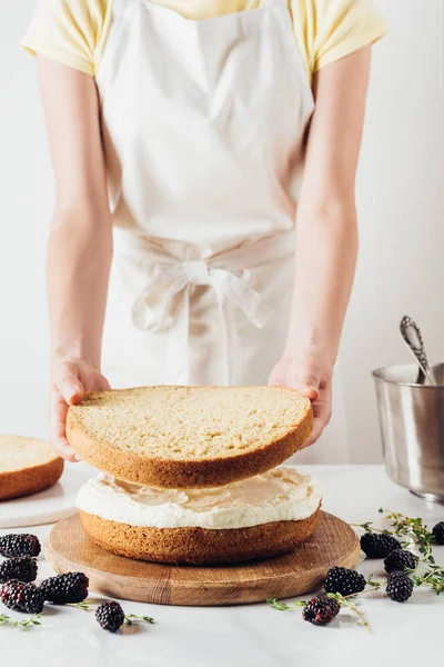 Tiro cortado de mulher fazendo delicioso bolo em camadas no branco — Fotografia de Stock