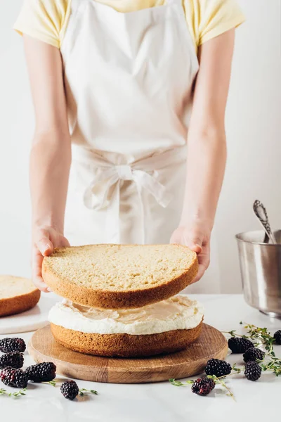 Recortado tiro de mujer haciendo delicioso pastel en capas en blanco - foto de stock