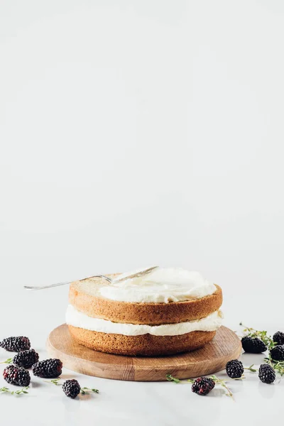 Pastel recién horneado en tablero de madera durrounded con moras en blanco — Stock Photo