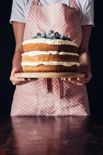 Cropped shot of woman holding tasty blackberry cake on plate — Stock Photo