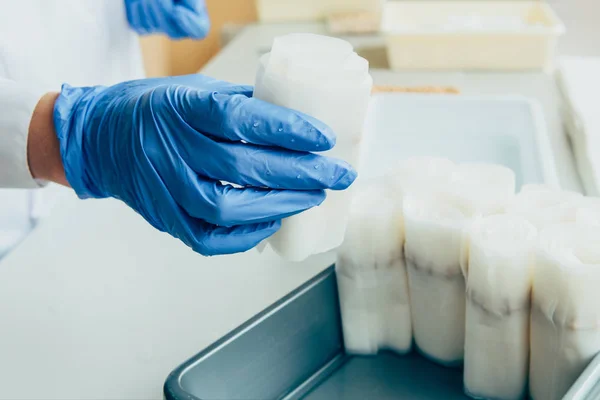 Cropped image of scientist in latex gloves putting paper with seeds in modern laboratory — Stock Photo