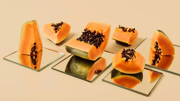 Papayas spiegeln sich in Spiegeln auf beigem Tisch — Stockfoto